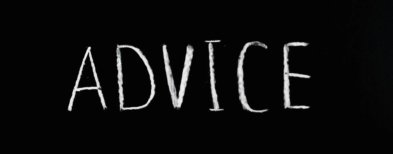 Wit krijtwoord "ADVICE" op een zwarte achtergrond als symbool voor advies of begeleiding