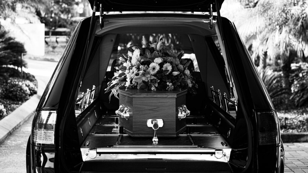Rouwauto met kist en bloemen tijdens ceremonie bij afscheid regelen na een overlijden