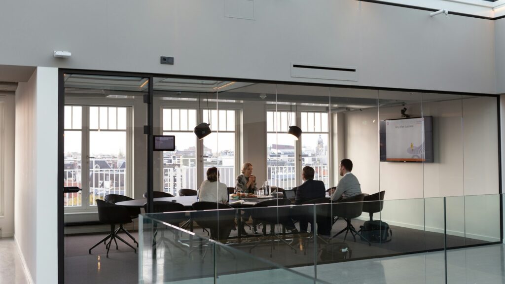 Ondernemers in glazen vergaderruimte bespreken zakelijke kansen met uitzicht over de stad