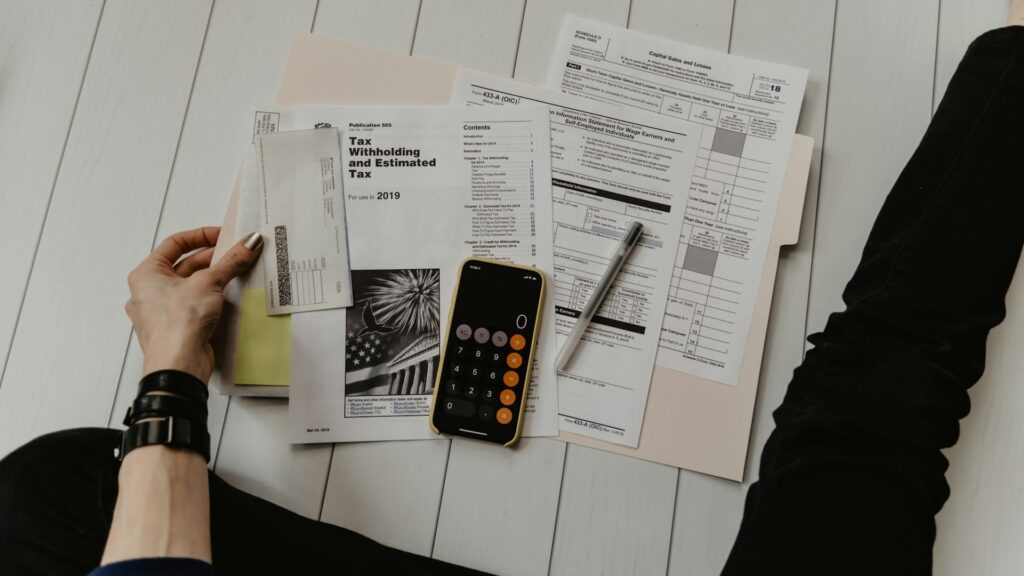 Hulp bij belastingaangifte met documenten, rekenmachine en papieren formulieren op tafel