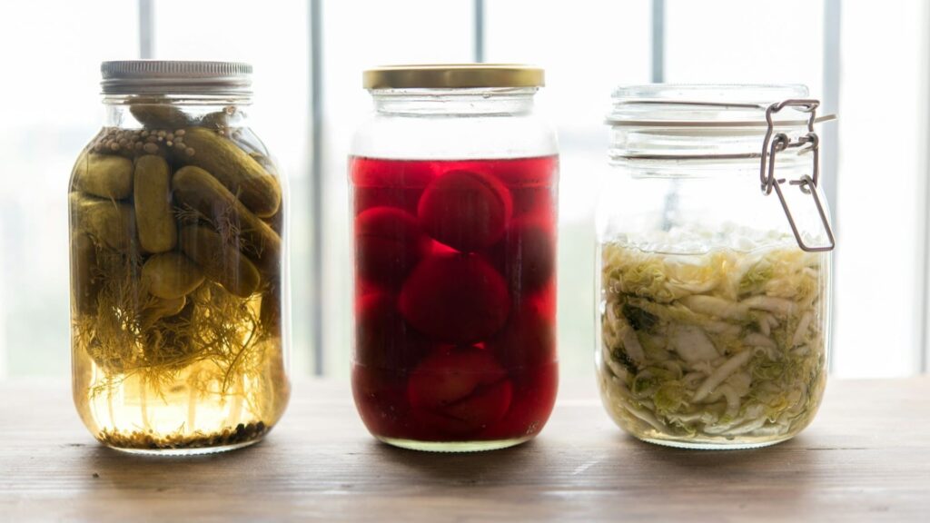 Glazen potten met gefermenteerde groenten en vloeistoffen tijdens gefermenteerde drank maken proces op houten tafel