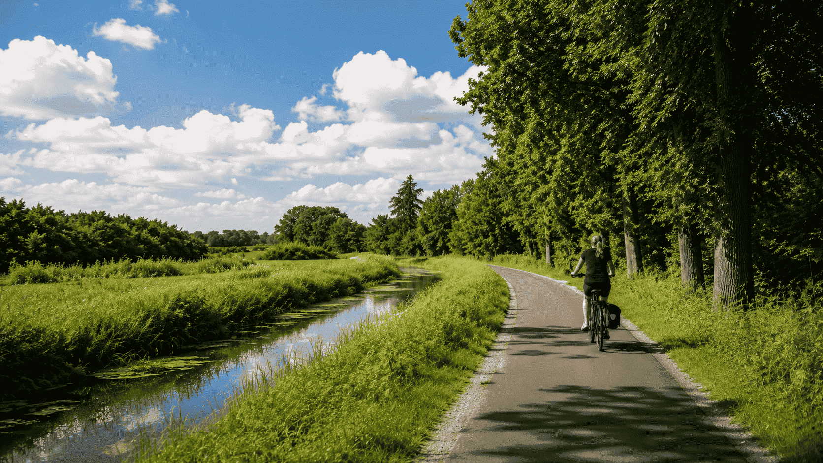 Een vrouw die een fietsroute langs het kanaal fietst